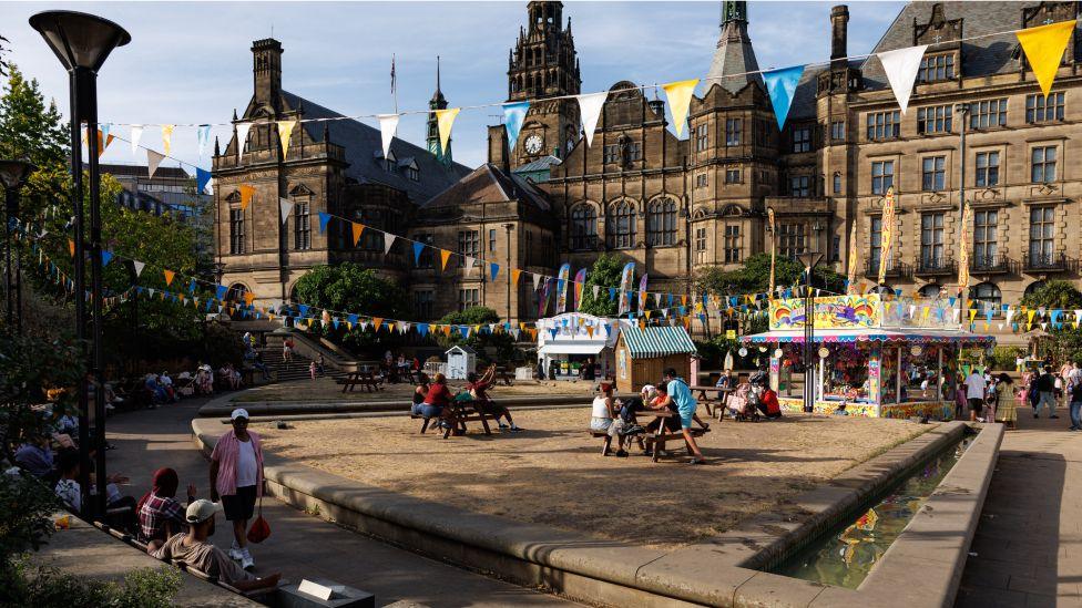 Members of the public gather at the Peace Gardens in Sheffield, England, on August 11, 2026, during a seaside-themed event.