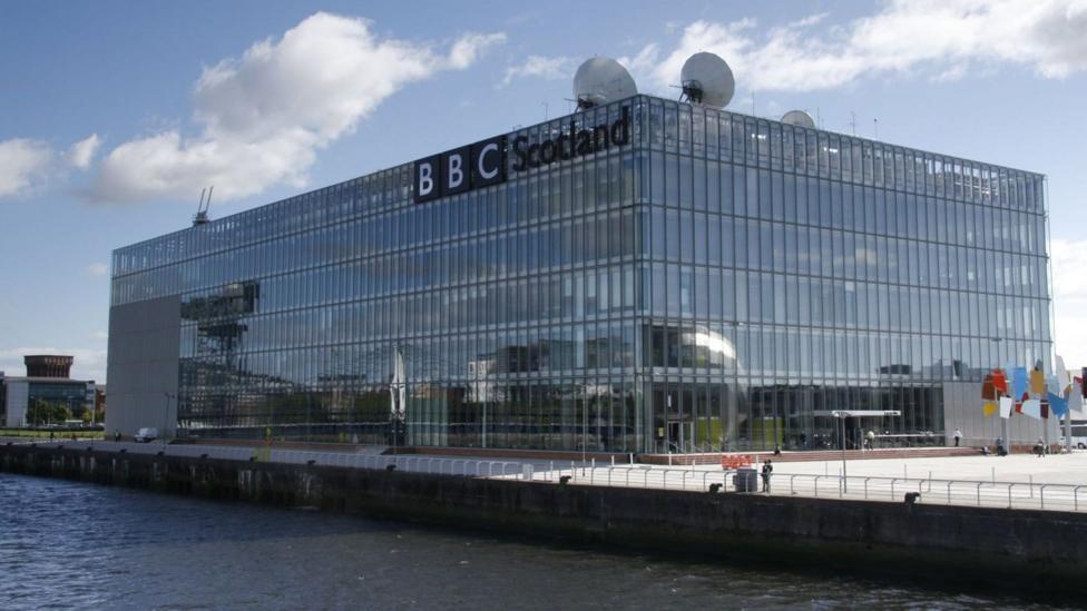 Katta yozuvda 'BBC Scotland' degan yozuv bor katta kvadrat derazali bino. Uning tepasida antennalar turibdi.