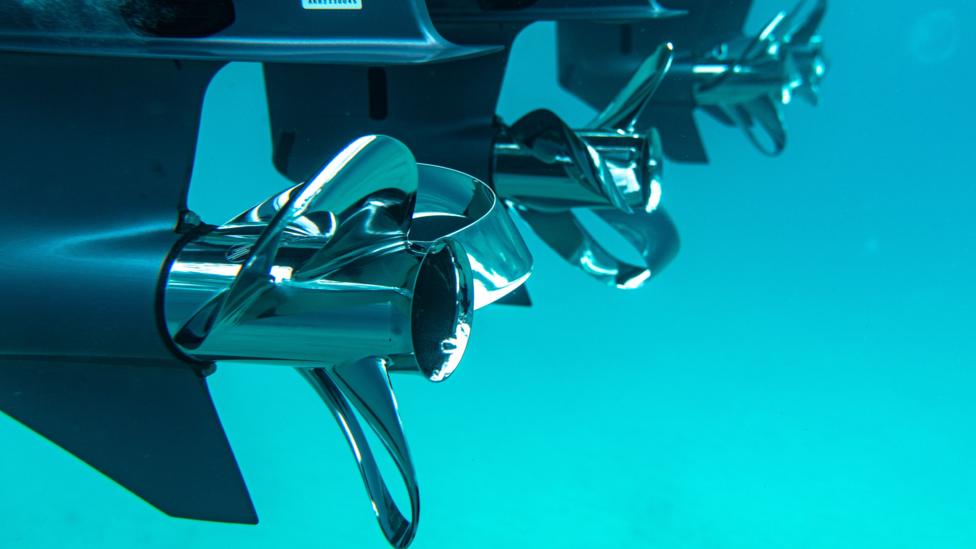 Sharrow Engineering boat propellers underwater. The blades twist back on themselves, almost like a bow.