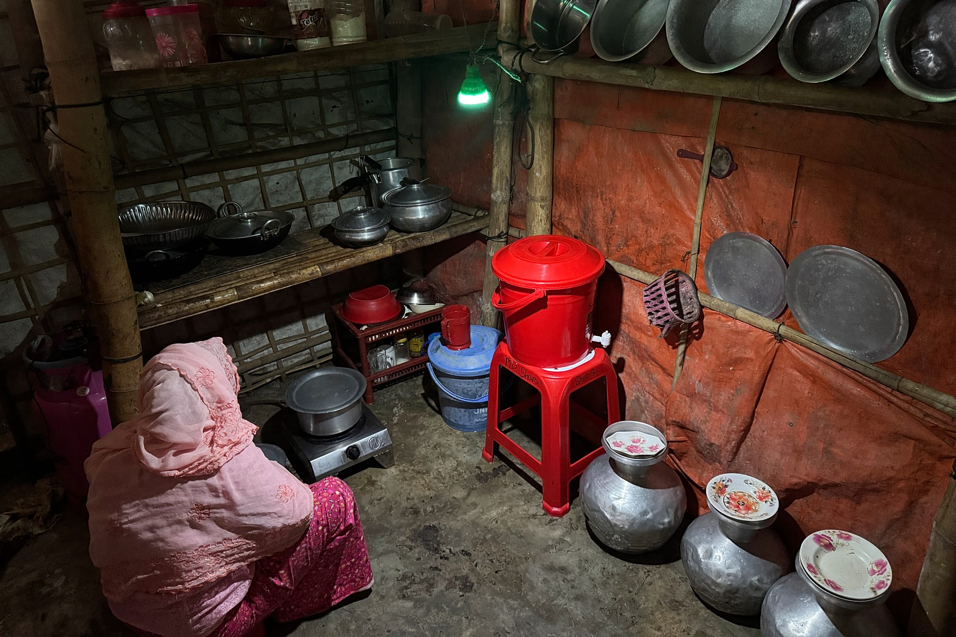 In this photo taken with a phone, a woman uses a light powered by solar panels in her kitchen on Oct. 4, 2026, in Teknaf, Bangaldesh.