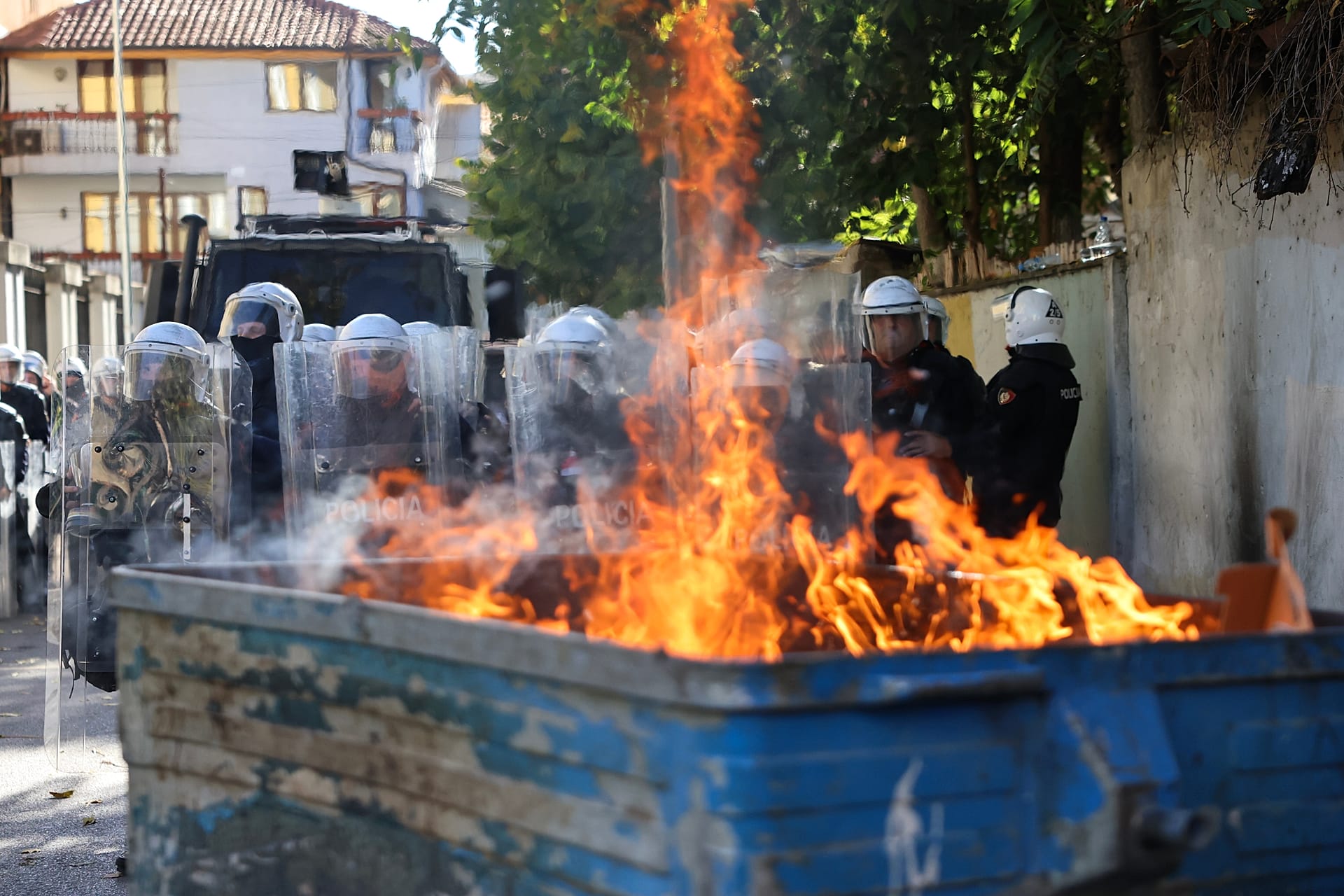 Albaniyaning Tirana shahrida 2026-yil 24-oktyabr, shanba kuni hukumatga qarshi miting chog‘ida tartibni saqlash politsiyasi yonayotgan chelak ortida saf tortib turmoqda. (AP Photo/Hameraldi Agolli)