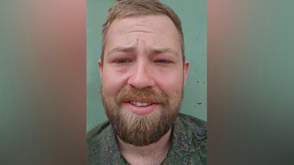 У Натана Стоббарта короткие тёмно-землянично-русые волосы, усы и борода. На нём армейская зелёная камуфляжная рубашка с расстёгнутым воротом, он слегка щурится. Глаза выглядят немного опухшими. Стена позади него бирюзово-голубая.