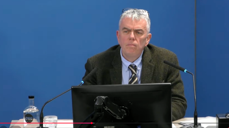 Man in dark jacket and tie gives evidence