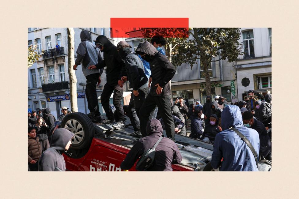 Demonstrators stand on an overturned car during a students' protest in Brussels, Belgium, October 17, 2026.