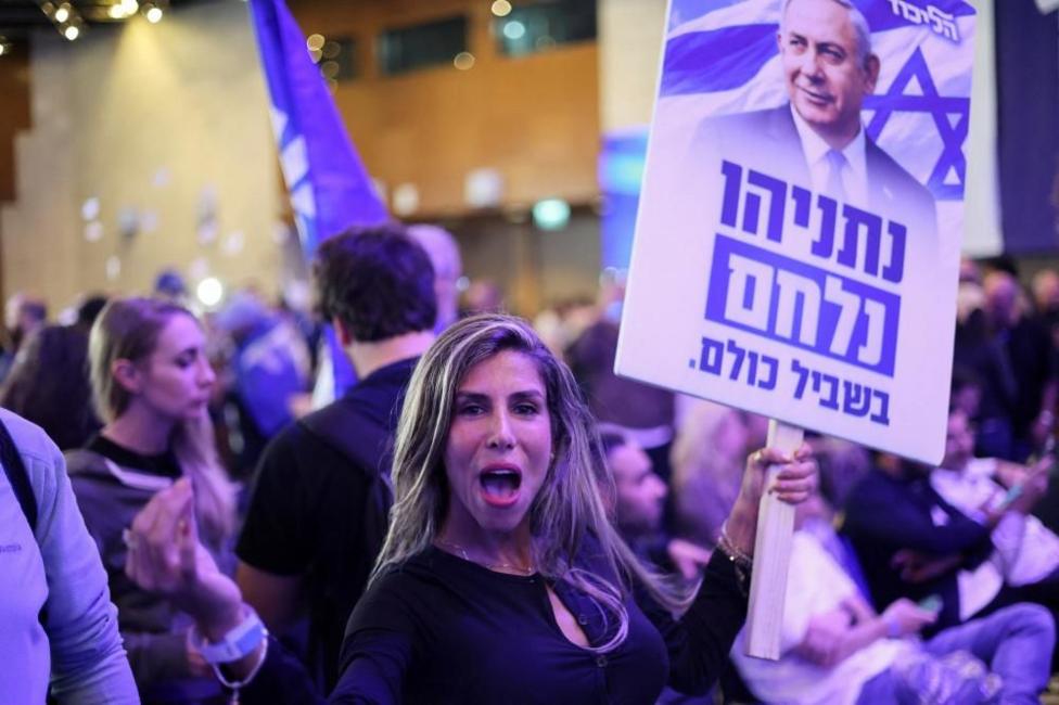 Ayol Netanyaxu tasviri tushirilgan plakatni ko‘tarib turibdi.