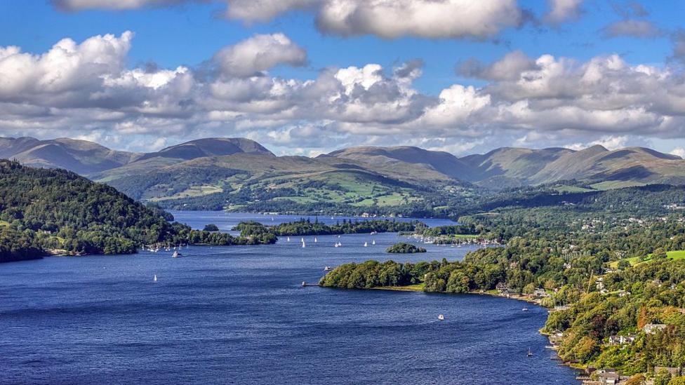 An aerial view of Windermere surrounded by lush green trees.