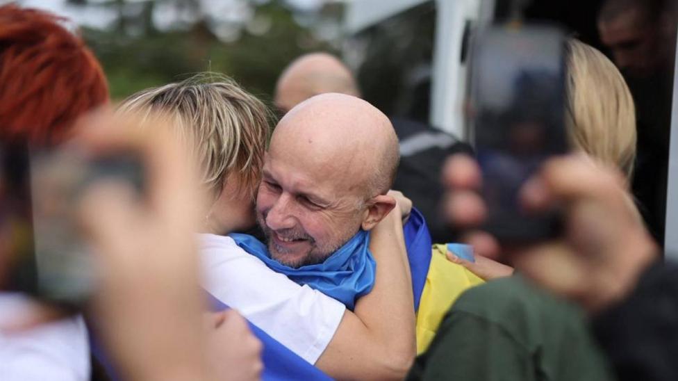 A Ukrainian man held in Russia for three and a half years grins and hugs a woman on his release in August 2025