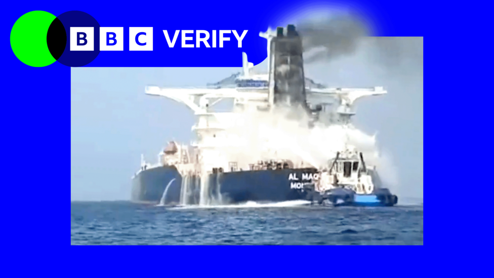 A tanker with a blue hull and white superstructure has water sprayed on it from a smaller vessel after an apparent attack
