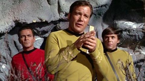 Uilyam Shatner kapitan Jeyms T. Kirk rolini aloqa qurilmasiga gapirayotgan holda, yonida Jeyms Duxan Montgomery «Scotty» Scott va o‘ngda Uolter Koenig Pavel Chexov rollarida, 1968-yilgi Star Trek epizodida