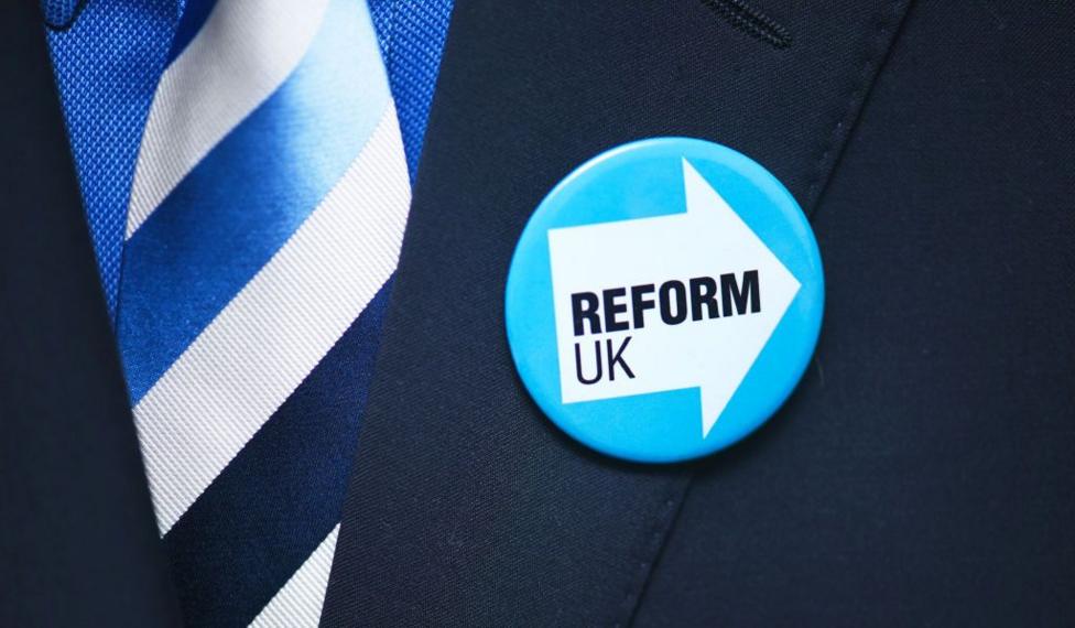 A Reform UK badge on a suit