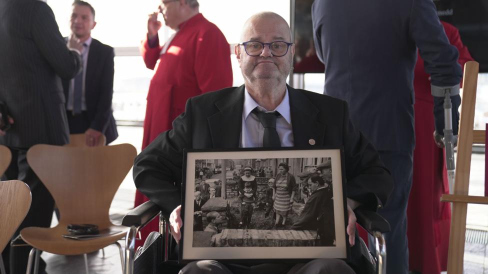 Gareth Jones holding a black and white picture of the King's father meeting him and his sister after the Aberfan disaster.