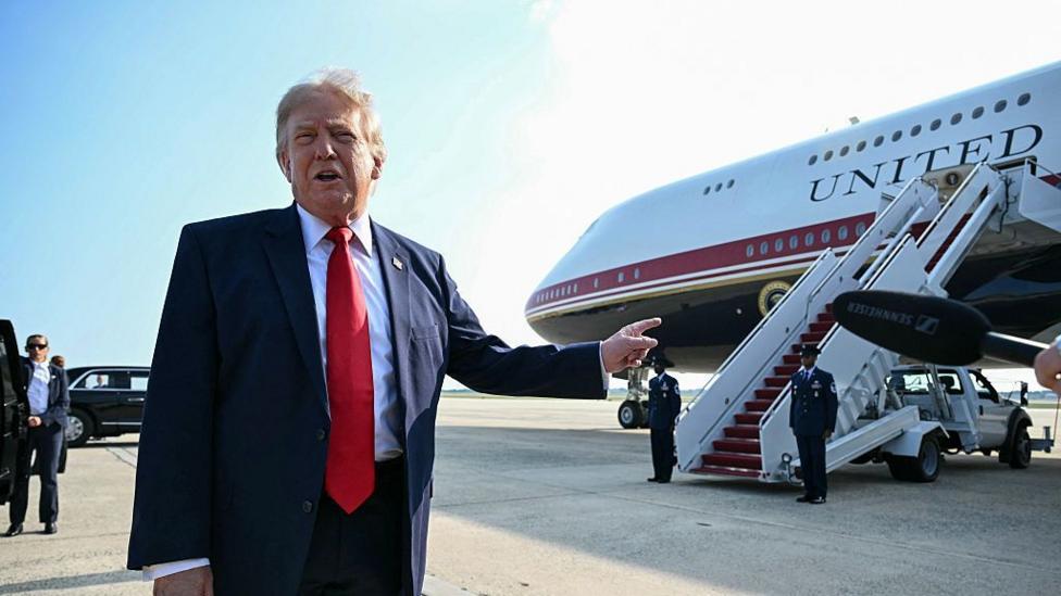 AQSh prezidenti Donald Tramp aeroport maydonida Qatar hadya qilgan va Air Force One vazifasini bajarayotgan samolyotga ishora qilmoqda