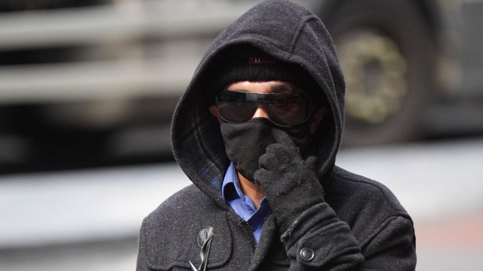 Kashim Chowdhury wears dark sunglasses, a hat, hoody and gloves as he arrives at court. His face is largely obscured.