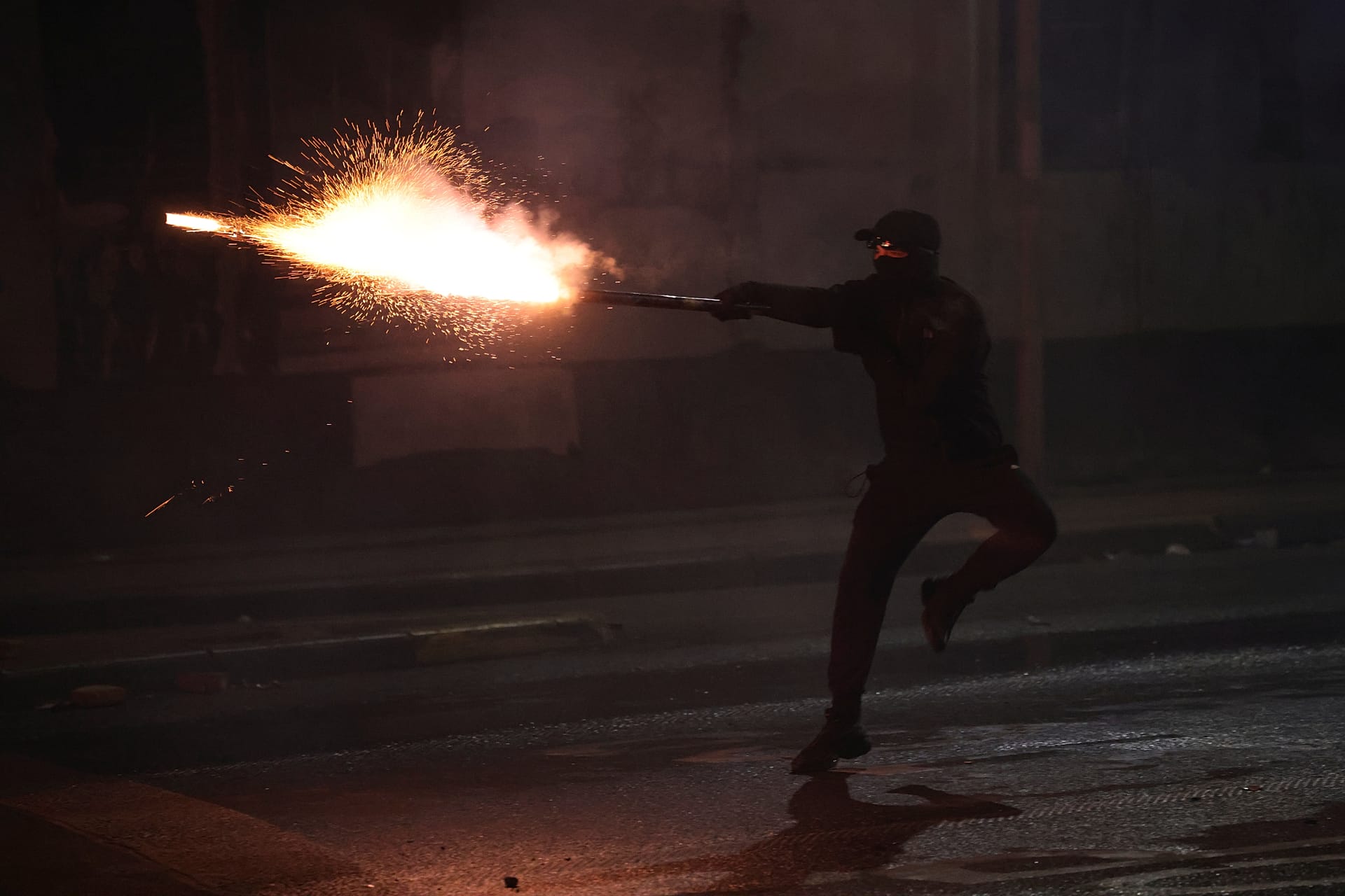 A hooded protester aims fireworks at police during clashes at an anti-government demonstration in Tirana, 18 October, 2026