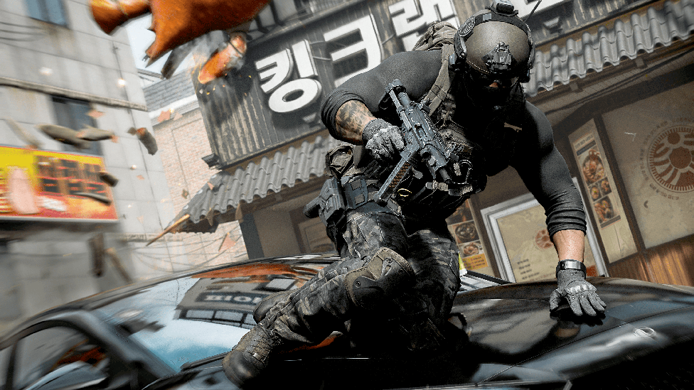 Кадр из Call of Duty Modern Warfare 4: солдат перепрыгивает через машину на улице южнокорейского города. На нём шлем и защитное снаряжение, в руках большой автомат.