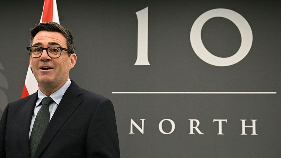 Энди Бёрнэм улыбается, стоя перед табличкой Number 10 North.