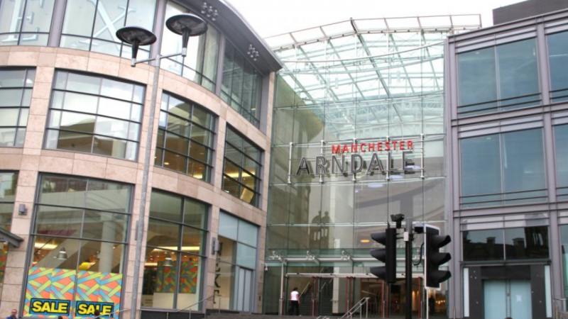 A woman walks in front of the glass-fronted Manchester Arndale shopping centre