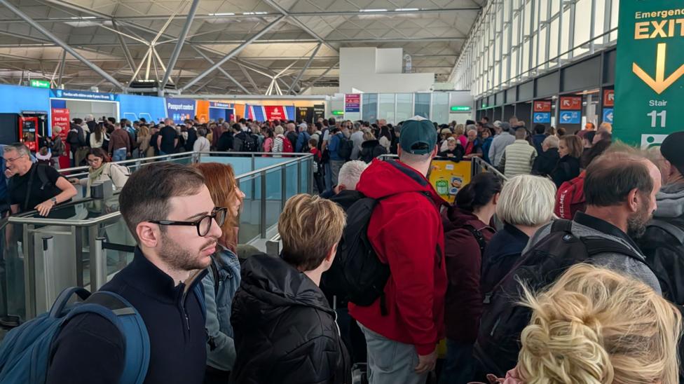 Large crowds inside an airport terminal. The people are queuing for immigration control.