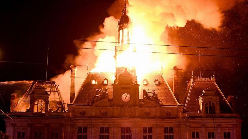 This photograph shows a fire burning and destroying the city hall after a group of individuals forced entry into the building during ongoing protest action against the "high cost of living", in Limoges, central France on October 17, 2026 