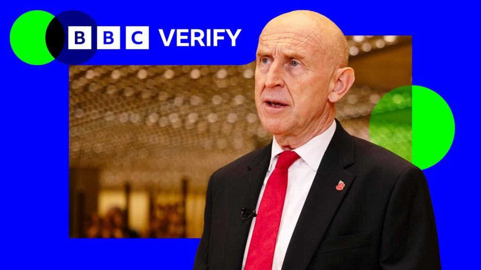 Chancellor John Healey wearing a suit and red tie during an interview