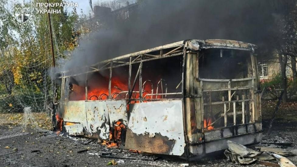 Горящий металлический каркас автобуса в Краматорске. Внутри автобуса видны языки пламени, наружу идёт чёрный дым, дорога усыпана обломками