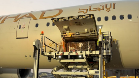 A large brown container is seen being placed inside a large grey aircraft.