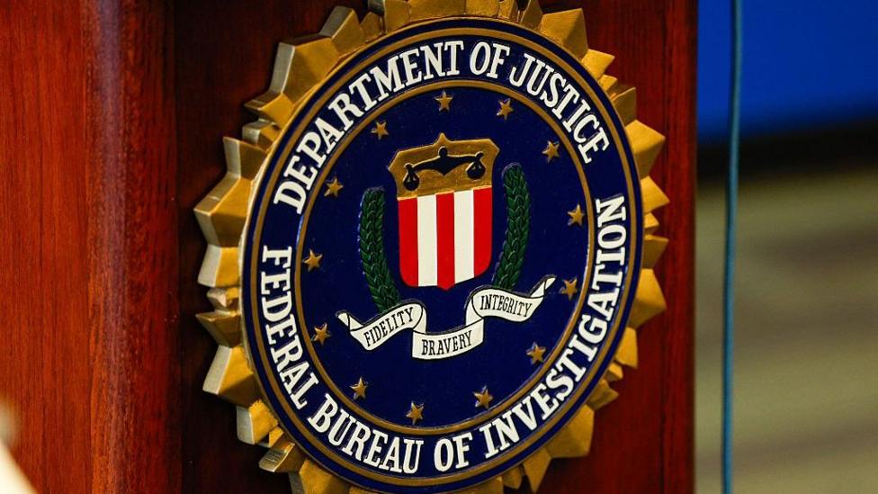 Close-up of a logo on a podium reading "Department of Justice, Federal Bureau of Investigation" 