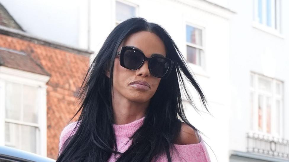 A woman with straight black hair. She is wearing big black glasses. 
