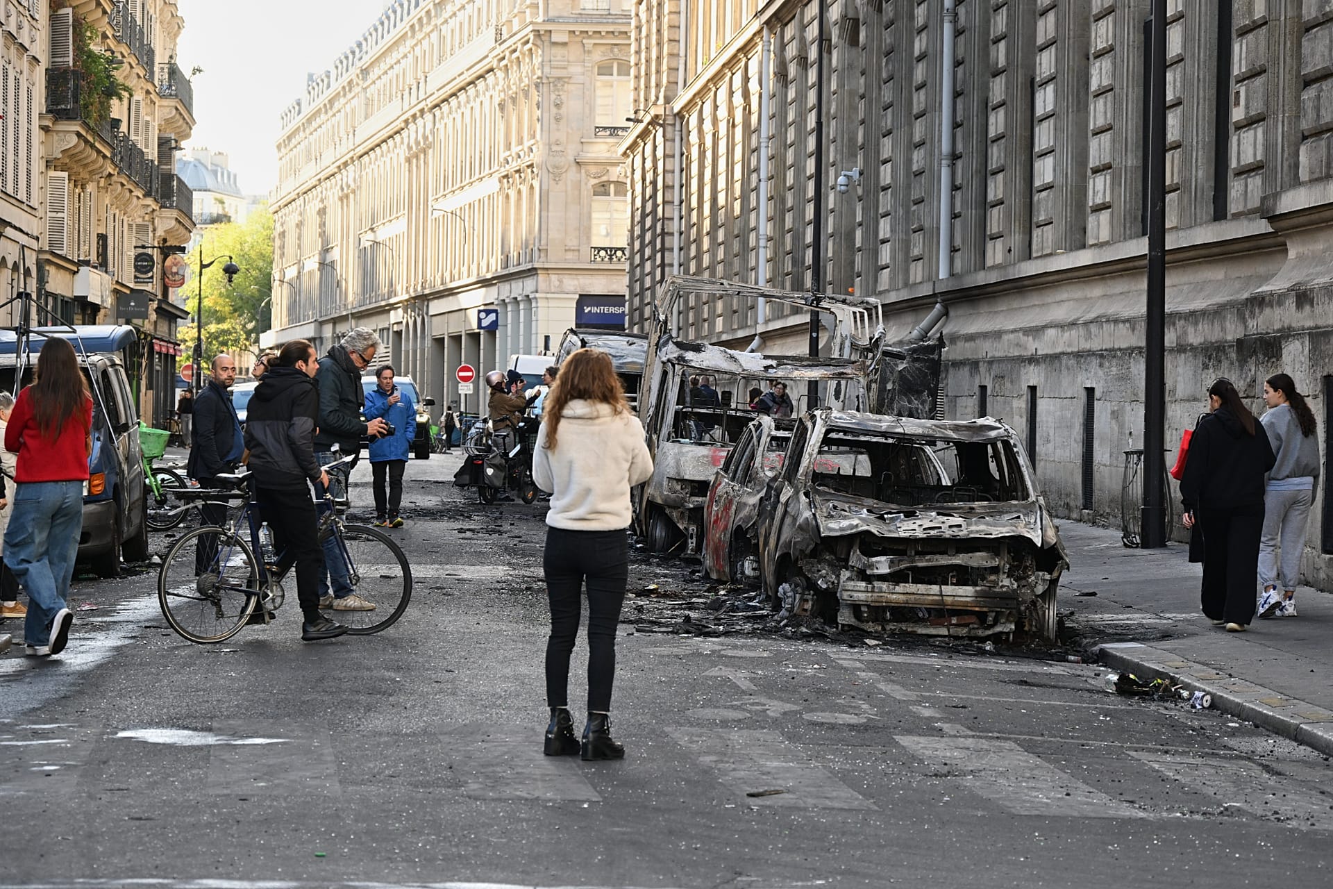 People look at charred cars the day after a demonstration against rising living costs, joining students' grievances, in Paris, Sunday, Oct. 18, 2026.