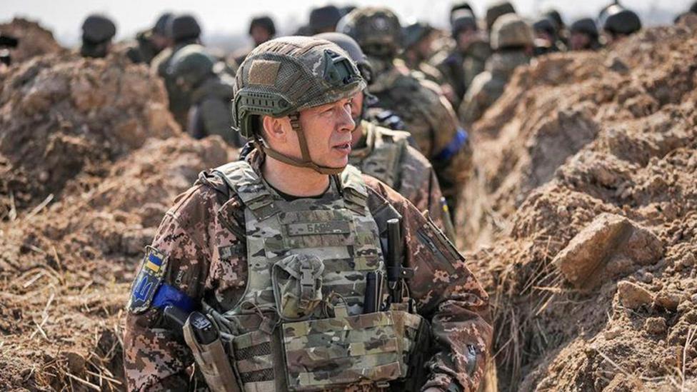 Gen Oleksandr Syrskyi walks in a trench in front of other soldiers.