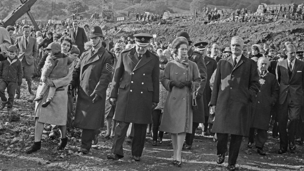 The Queen walking through the rubble of Aberfan. It is a black and white image, she is not smiling.