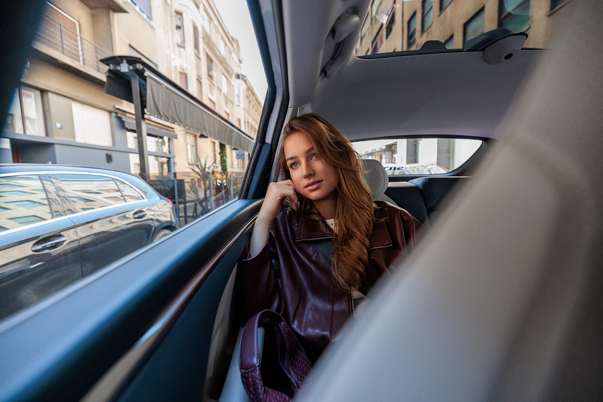 A woman sits and looks out the window during her taxi ride.