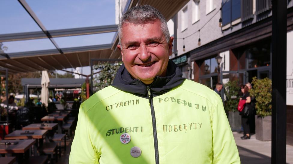 A man in a yellow top with the legend Students Win written in Serbian