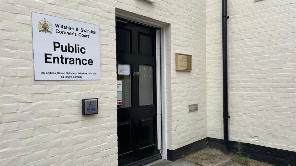 A black door with a sign next to it which says 'Wiltshire and Swindon Coroner's Court'