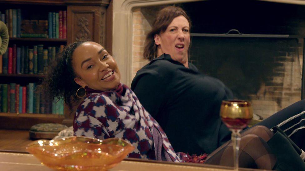 Leigh-Anne and Miranda sitting on the floor and leaning backwards in the middle of a dance move