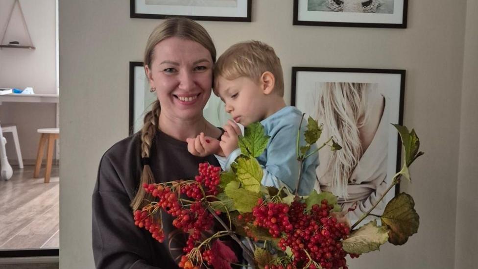 Светловолосая женщина держит ребёнка на руках