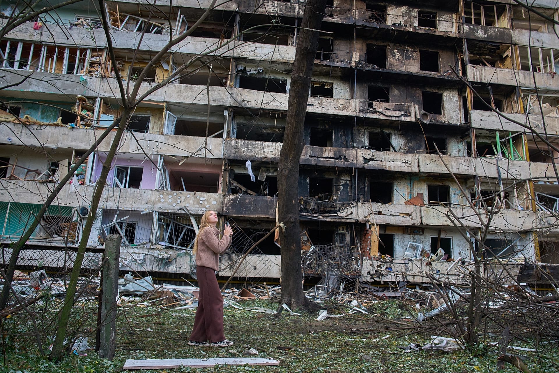 A young woman reacts as she looks at her damaged home after Russia's night missile attack in Kyiv, 14 October, 2026