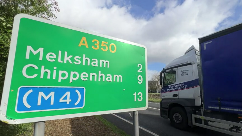 A green sign which says 'A350' and the Melksham, Chippenham and M4 beneath. A lorry passes in the background.