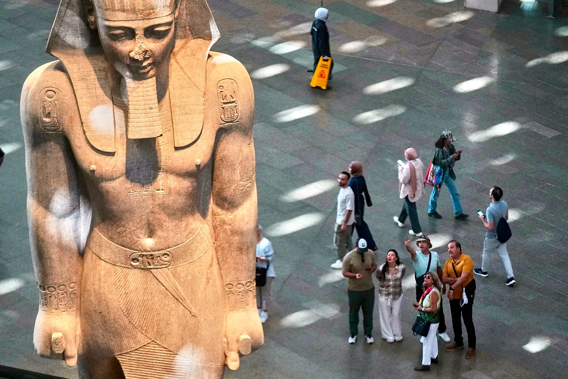 Visitors beside a statue of Ramses II at the Grand Egyptian Museum in Giza, Egypt, on 4 November 2025.