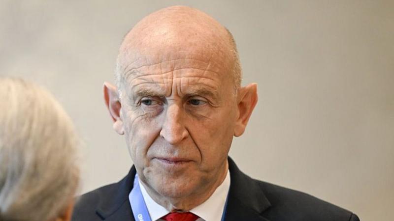 John Healey, chancellor of the UK, speaking to a woman at the IMF annual meeting in Bangkok, Thailand, earlier this month. He is wearing a black suit with a white shirt and red tie.
