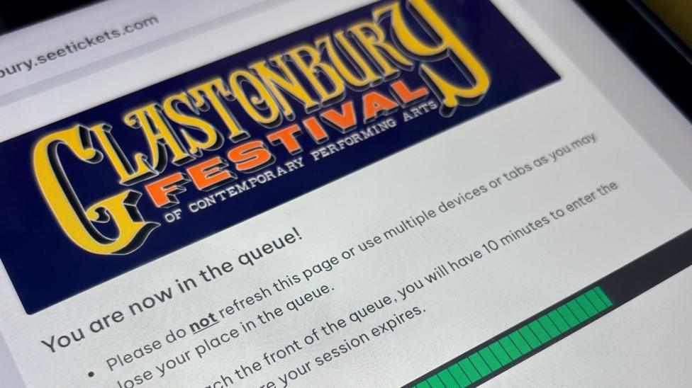 A screenshot from the See Tickets website showing the queue for Glastonbury Festival tickets, with a green loading bar and the festival's logo on a dark blue banner.