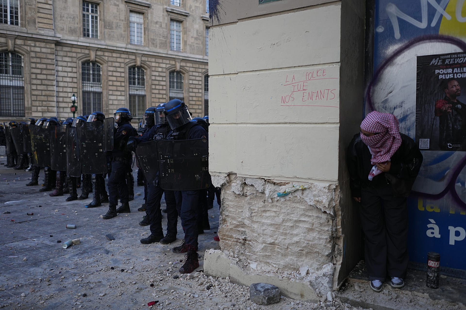 A protester watches riot police during a demonstration against rising living costs, joining students' grievances, in Paris, Saturday, Oct. 17, 2026