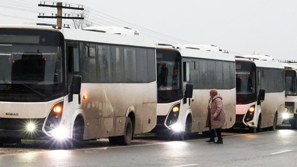 Rossiya nazoratidagi Oleşki şahridan evakuatsiya qilingan aholini olib ketayotgan oq avtobuslardagi gumanitar konvoy, 2026-yil 30-oktabr, Qrimdagi yö çetida qisqa töxtaş paytida körsatilgan.