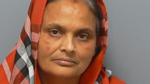 Kiran Kaur looking at the camera, with a red checked head scarf on her head.
