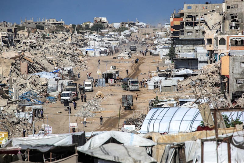 Vehicles drive past collapsed buildings and temporary shelters in the Jabalia camp in the northern Gaza. AFP