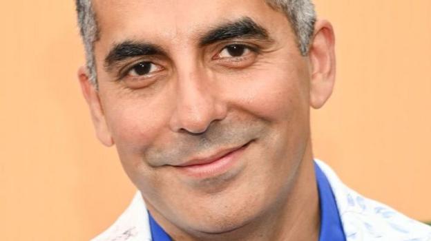 Sunil Malhotra smiling while wearing a white jacket