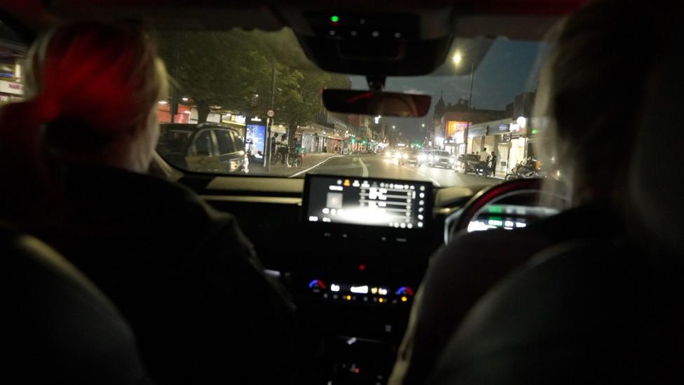 The backs of two female officers on patrol in a car at night 