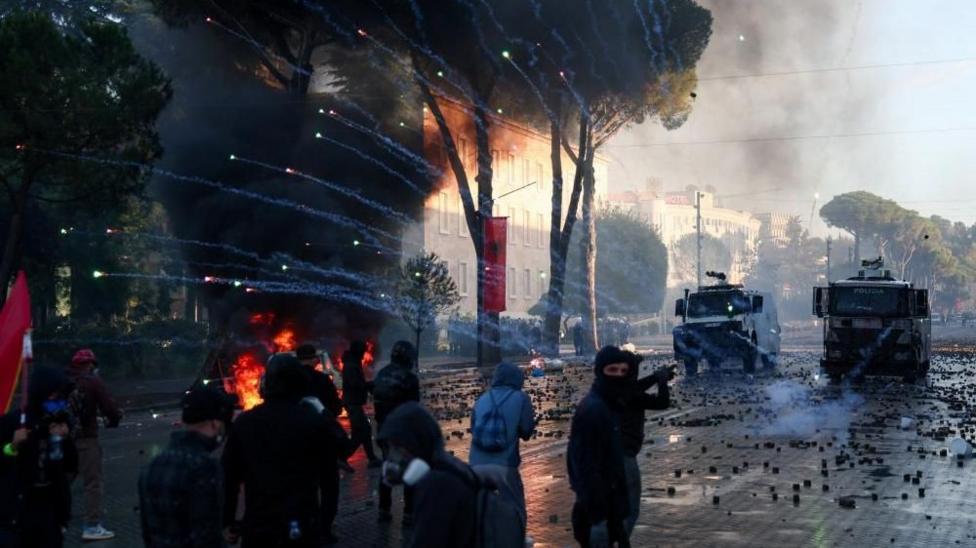 Fireworks exploding over protesters and riot police vans