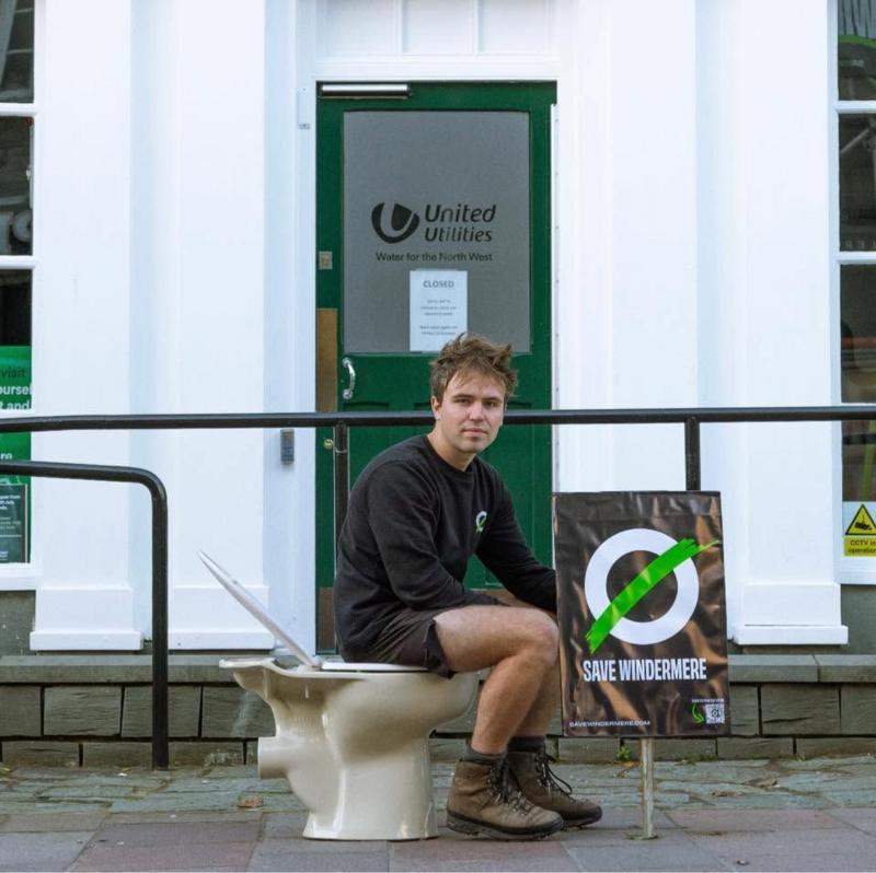 Matt Staniek sits outside the offices of United Utilities on a toilet.
