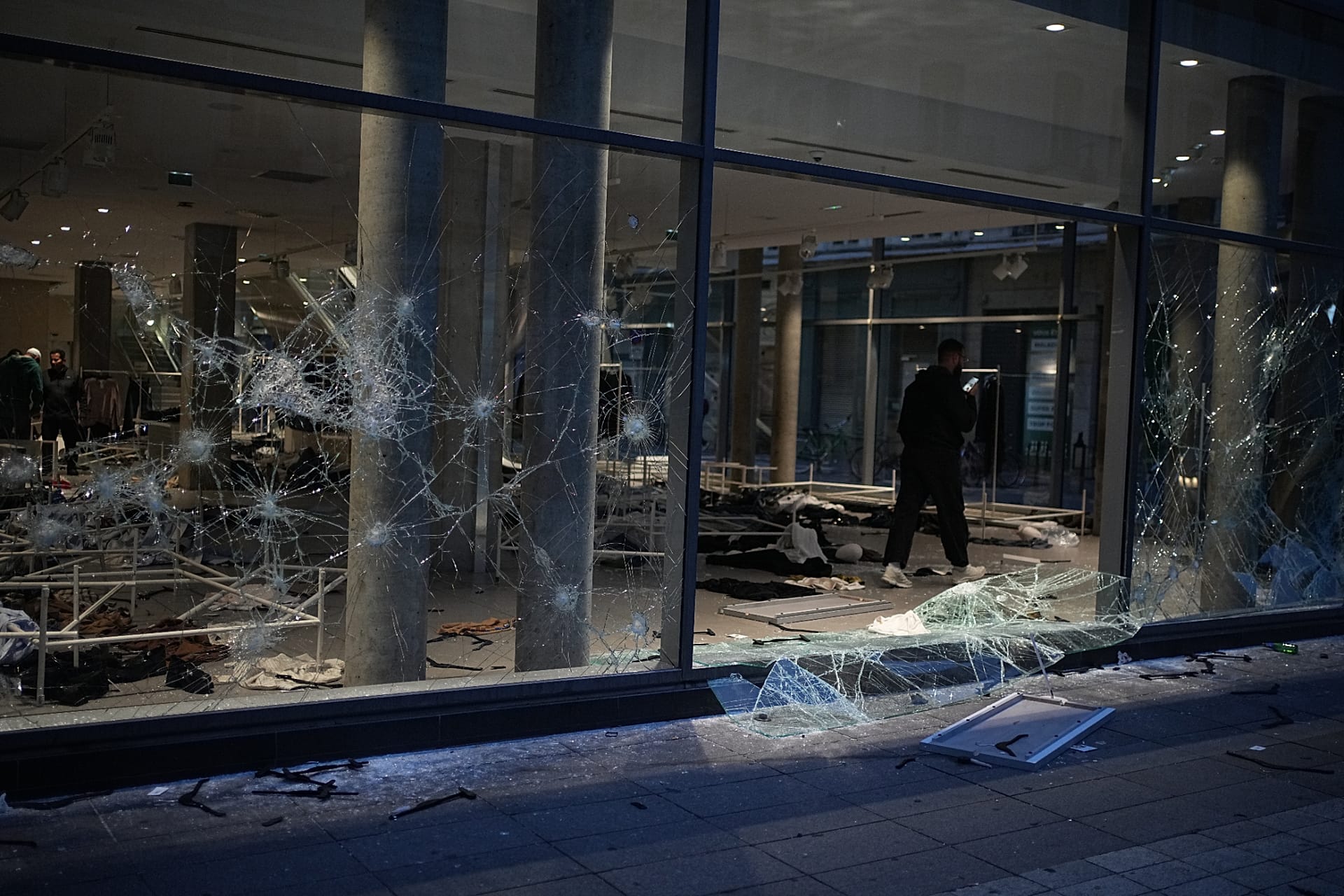 A man takes photos of a looted store after a demonstration against rising living costs, joining students' grievances, in Lyon, France, Saturday, Oct. 17, 2026.